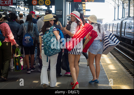 Sun e gli amanti del surf arrivano alla stazione di Stillwell a Coney Island a Brooklyn in New York Foto Stock