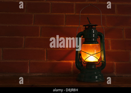 Una lampada ad olio lanterna illuminazione di stile nella parte anteriore di un brickwall sfondo. Foto Stock