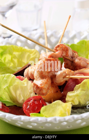 Spiedini di pollo e le strisce di pancetta servita su foglie di lattuga Foto Stock