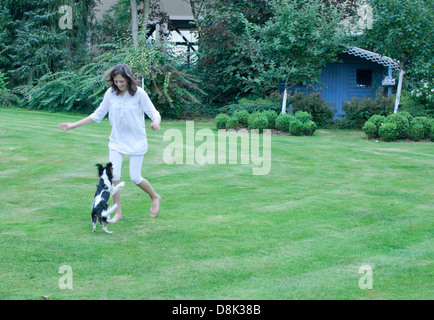 Ragazza che gioca con il cane in cortile Foto Stock