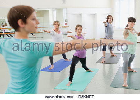 Donna istruttore la pratica dello yoga con studenti in studio di yoga