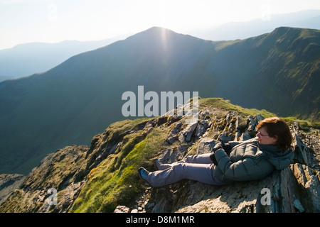 Una femmina di escursionista sdraiato sul vertice della testa Hopegill all alba con Grisedale Pike nella distanza. Lake District Foto Stock