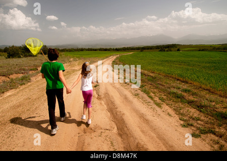 Bambino e bambina con reti a farfalla a piedi su un prato. Foto Stock