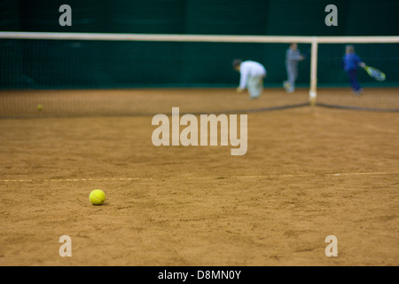 Palla da tennis sulla corte e i ragazzi in background Foto Stock