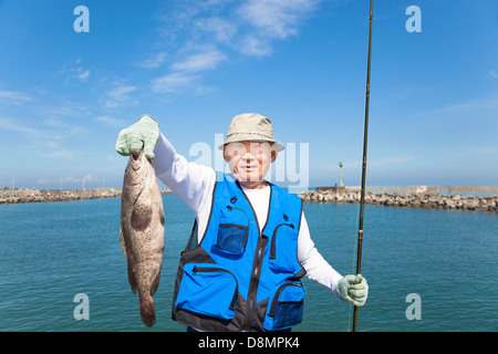 Felice asian senior pescatore che mostra grande raggruppatore Foto Stock