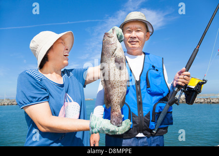 Felice asian coppia senior pesca e mostrando grande raggruppatore Foto Stock