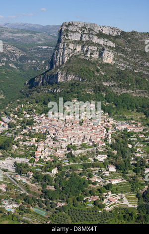 VISTA AEREA. Borgo medievale ai piedi di una massiccia scogliera alta 400 metri. Saint-Jeannet, Costa Azzurra, Alpes-Maritimes, Francia. Foto Stock