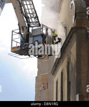 Una donna orologi dal suo balcone come i vigili del fuoco di mettere fuori un incendio presso la porta accanto Medina House edificio sul lungomare Hove nel tardo pomeriggio Foto Stock