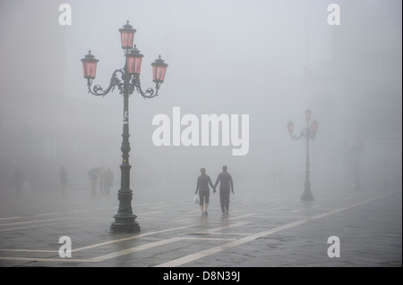 Un giovane a piedi in Piazza San Marco a Venezia coperti di fitta nebbia, Italia. Foto Stock