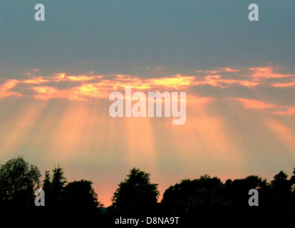 I raggi del sole si infrangono tra le nuvole, diffondendo la luce attraverso il paesaggio sottostante. L'immagine cattura la bellezza e il contrasto tra i raggi luminosi e la spettacolare copertura delle nuvole. Foto Stock