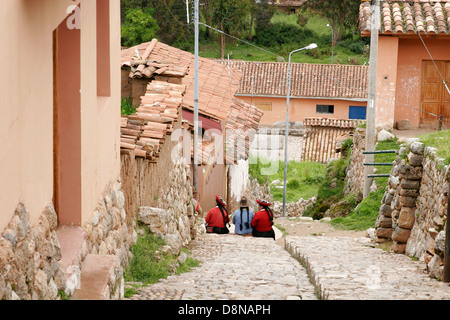 Tre donne indigene seduti sulla strada di Chinchero, tipico villaggio andino nei pressi di Cuzco, Perù, Sud America Foto Stock