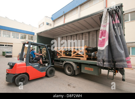 Un carrello di caricamento di un carrello elevatore con un pallet irregolari di tubazioni in plastica Foto Stock