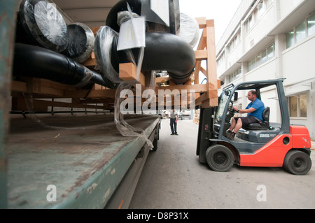 Un carrello di caricamento di un carrello elevatore con un pallet irregolari di tubazioni in plastica Foto Stock