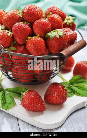 Rosso fresco fragole in un grande cesto di metallo su sfondo di legno Foto Stock