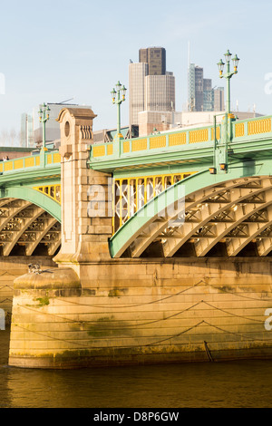 Travi di supporto Bridge Southwark attraverso il Tamigi a Londra con il sole di setting illuminazione il dipinto di elementi in ferro battuto Foto Stock