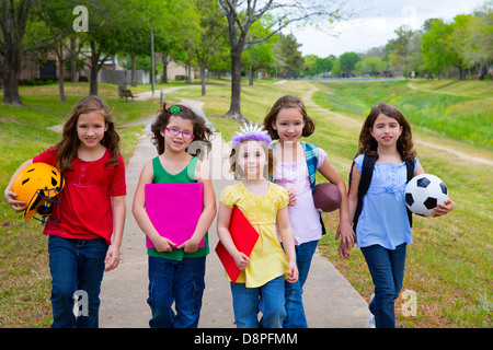 Bambini Bambino le ragazze a piedi schoool con sport palle di cartelle e zaini in parco all'aperto Foto Stock