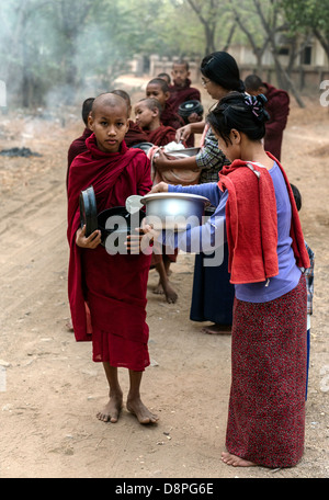 I monaci buddisti raccogliendo elemosine ciotole di cibo al mattino da abitanti di un villaggio vicino a Bagan Birmania Myanmar Foto Stock