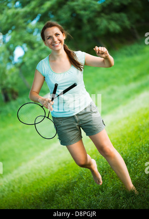 Felice, sorridente ragazza con una racchetta per badminton nel parco Foto Stock