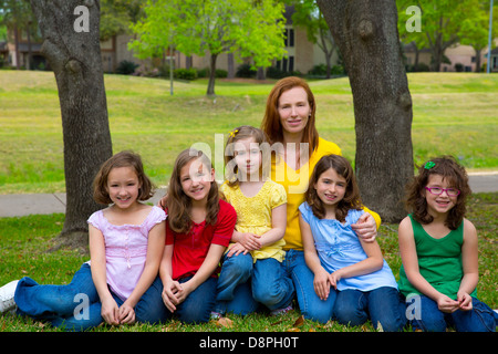 Insegnante di madre in figlia gli allievi nel parco giochi ritratto di gruppo sul prato Foto Stock