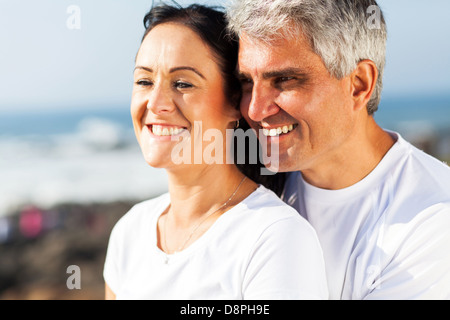 Felice metà età marito e moglie abbracciando in spiaggia Foto Stock