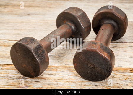 Una coppia di vintage ferro arrugginito pesi sul dipinto di bianco fienile Sfondo legno - Concetto di fitness Foto Stock