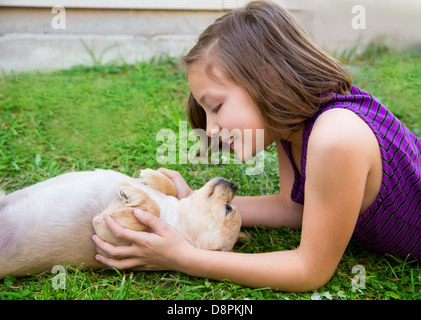 Bambini ragazza che gioca con il chihuahua cane sdraiato sul prato del cortile Foto Stock