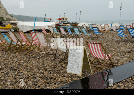 Occupati di sedie a sdraio e un avviso sul bagnato estate giornata in spiaggia di birra in Devon Foto Stock