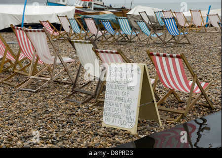 Occupati di sedie a sdraio e un avviso sul bagnato estate giornata in spiaggia di birra in Devon Foto Stock
