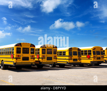 Tipico American School bus vista posteriore in una riga sotto il cielo blu giorno Foto Stock