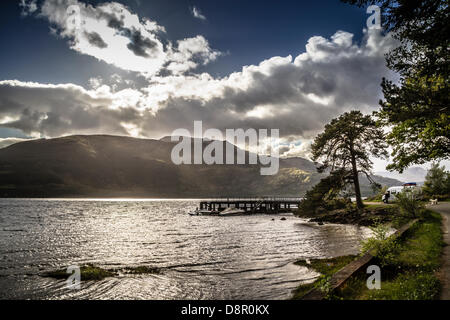 Rowardennan, Loch Lomond Scozia, Regno Unito - 3° giugno 2013. Splendido sole il peering attraverso le nuvole come turisti prendere una pausa gradita al molo. Foto Stock