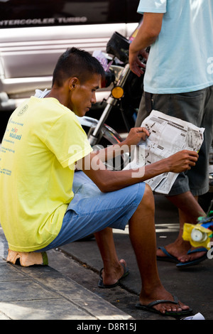 L'uomo la lettura di notizie per le strade di Manila, Filippine Foto Stock