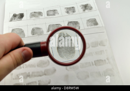 Confrontando le impronte digitali attraverso la lente di ingrandimento dattiloscopica vetro Foto Stock