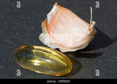 Un aglio in capsule contenente 1000 mg di aglio macerato con la quantità equivalente di aglio fresco (2400 mg) dietro. Foto Stock
