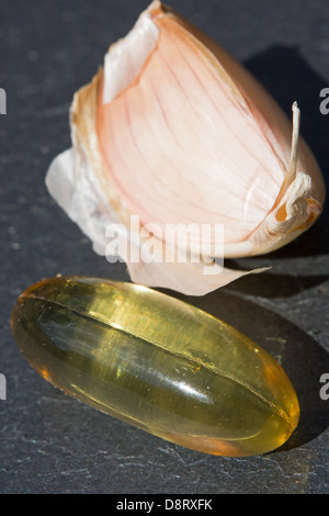 Un aglio in capsule contenente 1000 mg di aglio macerato con la quantità equivalente di aglio fresco (2400 mg) dietro. Foto Stock