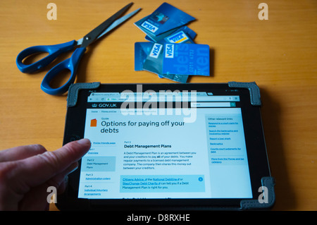 Persona che guarda nel Regno Unito il debito informazioni su internet su ipad mini tablet pc a casa Foto Stock