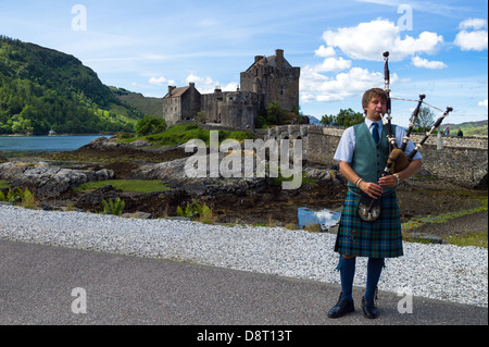 Gran Bretagna, Scozia, Highlands, un lettore delle cornamuse e il Eilean Conan castello in background. Foto Stock
