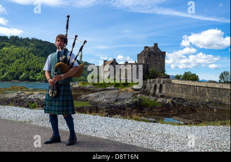 Gran Bretagna, Scozia, Highlands, un lettore delle cornamuse e il Eilean Conan castello in background. Foto Stock
