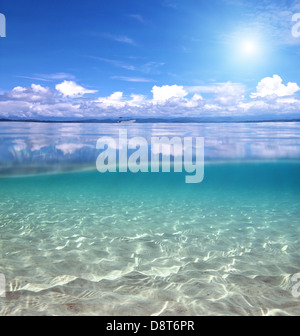 La vista suddivisa al di sopra e al di sotto di acqua nel Mar dei Caraibi con le nubi riflessi sulla superficie e un fondale sabbioso Foto Stock