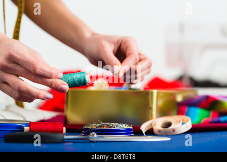 Freelance - adattare o designer che lavora con diversi utensili, come cotone bobine, spole, e tessuti colorati Foto Stock