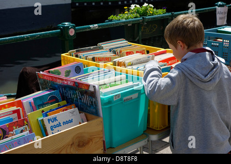 Ragazzo che guarda a seconda mano utilizzata fumetti a la Ajuinlei del mercato del libro a Gand, Belgio Foto Stock