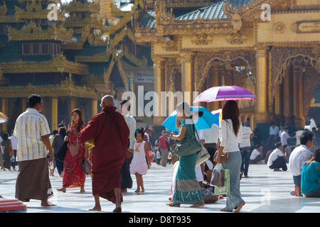 Adoratori, compreso un monaco, camminare a piedi nudi attraverso il marmo-area lastricata tra i molti templi della Schwedagon. Foto Stock