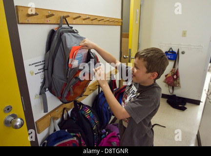 Maschio di 7 anni di primo grado studente prende progetto fuori di zaino nella scuola elementare aula in Texas Foto Stock