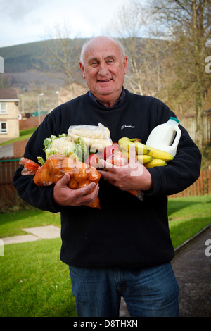 Un uomo detiene due armfuls di veg al di fuori della sua casa su un Galles del Sud immobiliare di alloggiamento che egli riceve da un veg co-op Foto Stock