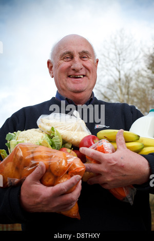 Un uomo detiene due armfuls di veg al di fuori della sua casa su un Galles del Sud immobiliare di alloggiamento che egli riceve da un veg co-op Foto Stock