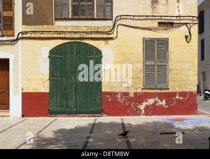 Un piccione passeggiate passato una tradizionale casa spagnola su Placa del pin, Ciutedella, Menorca, Spagna Foto Stock