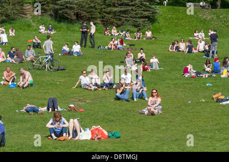 Grande gruppo di adulti di relax al sole in Kelvingrove Park, Glasgow, Scozia. Foto Stock