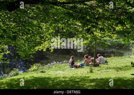 Gruppo di persone sedute al sole in stagno. Kelvingrove Park, Glasgow, Scotland, Regno Unito Foto Stock