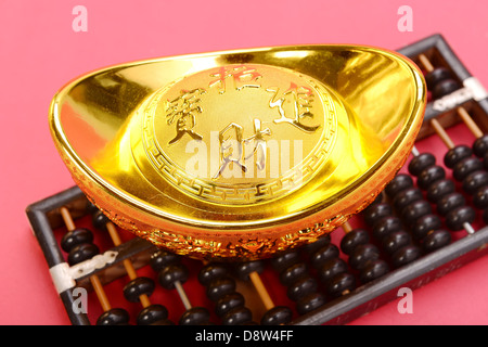 Cinese lingotto oro e abacus significa simboli di ricchezza e prosperità. Foto Stock