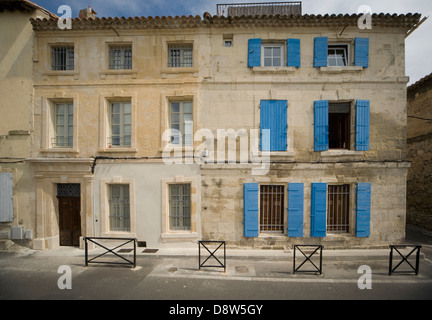 Due contigue antica pietra a 3 piani di case in Arles, Francia, uno con persiane blu su windows Foto Stock