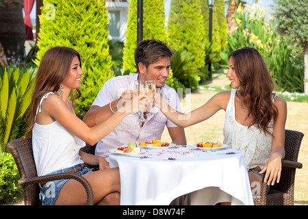 Tre amici durante la tostatura avente il pranzo all'aperto. Foto Stock